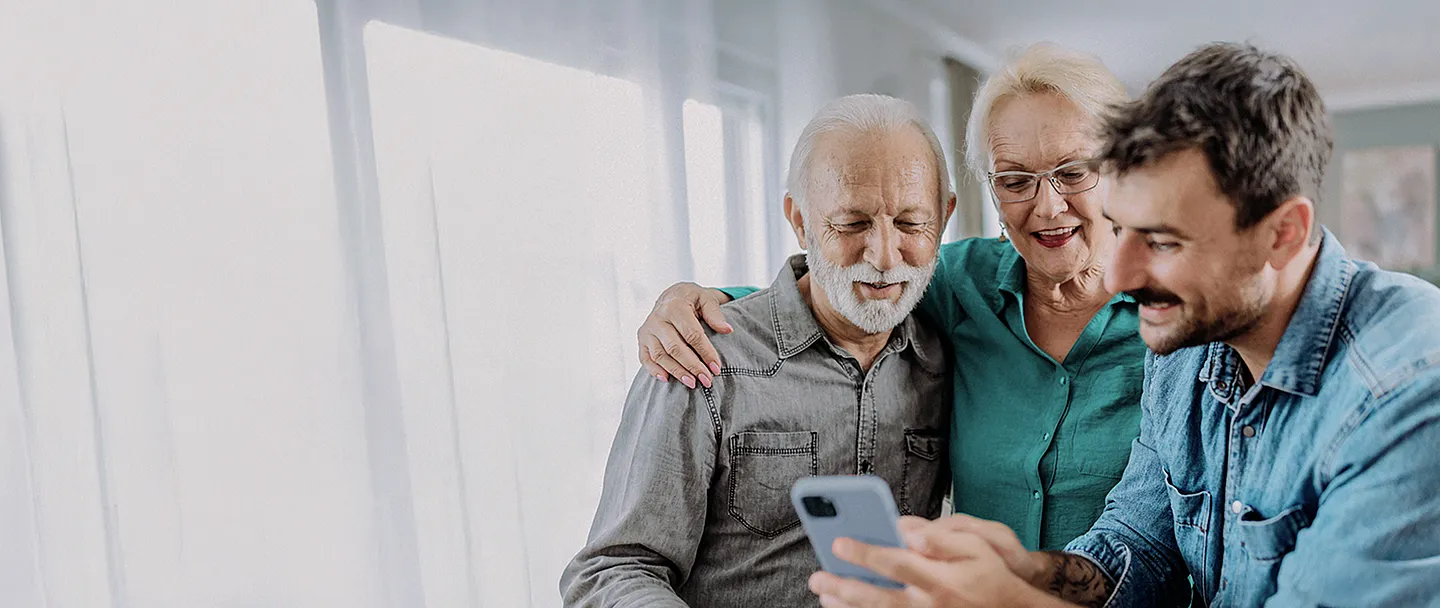 Der Sohn zeigt seinen Eltern etwas auf dem Smartphone.