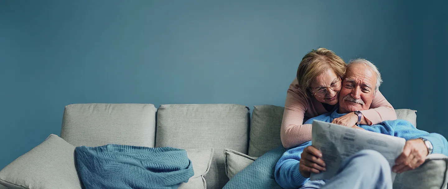 Ein Porträt eines älteren Paares, das zu Hause entspannt, redet, liest, kuschelt, genießt.
